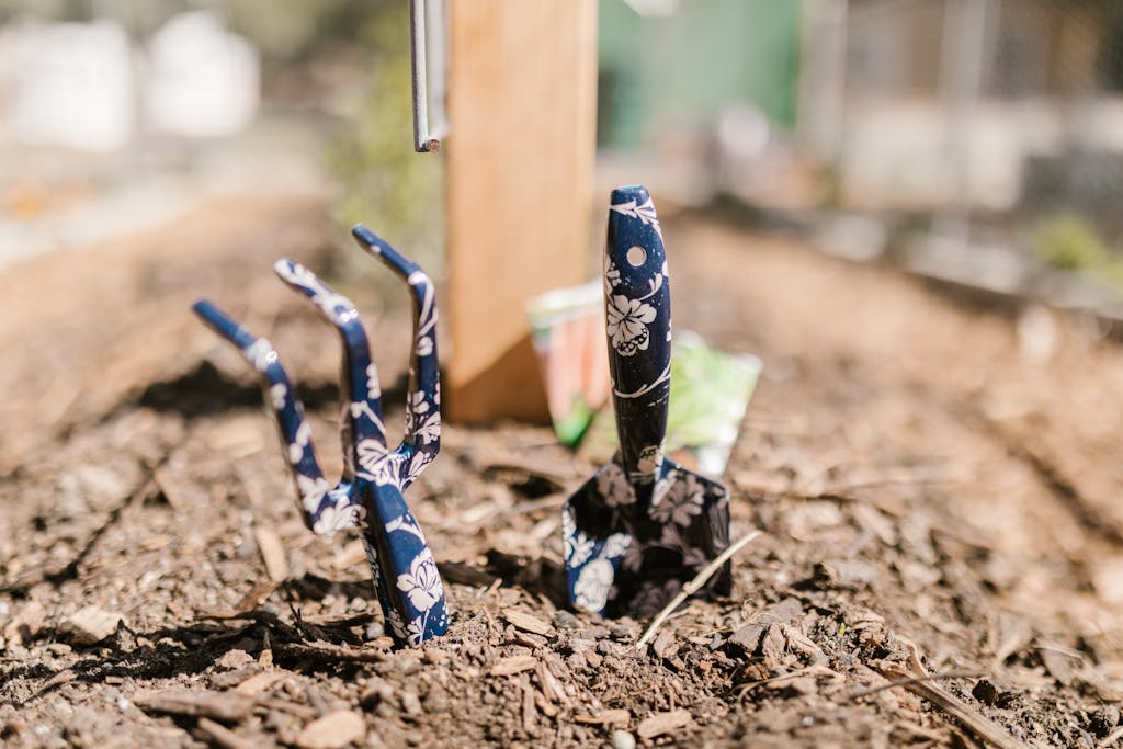A vibrant close-up of floral-patterned gardening tools in fresh soil, capturing the essence of gardening.